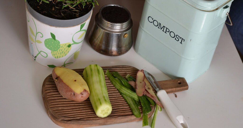 A peeled vegetable and cucumber next to a kitchen compost bin, a sustainable way to get compost for your potting mixes.